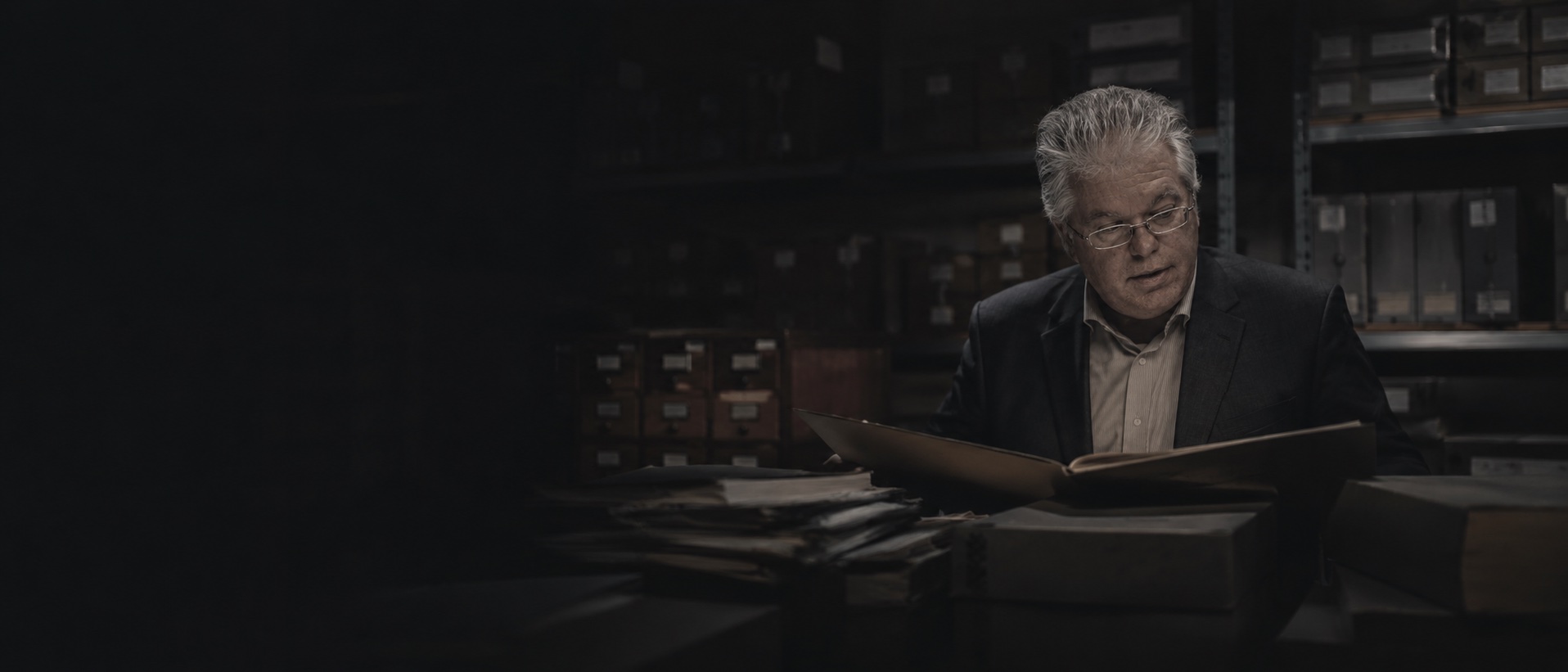 Éric Veillette consultant un dossier dans un dépôt d'archives : mise en scène numérique réalisée pour l'archive.